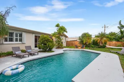 a swimming pool with two chairs and a house at Centrally Located 4BD Oasis with Pool & Movie Patio in Hollywood