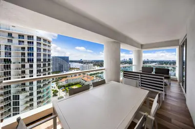 an apartment balcony with a white table and chairs at Beachfront Condo Fort Lauderdale in Fort Lauderdale
