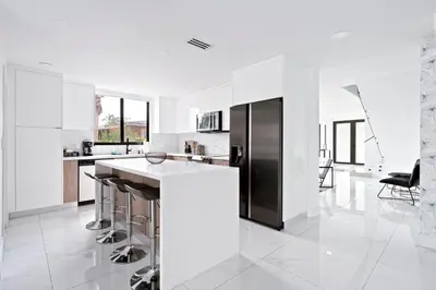 a white kitchen with a black refrigerator and stools at April Sale! 4BR - Private Yard, Grill, Soaking Tub, Near Coral Gables & MIA Airport in Tamiami
