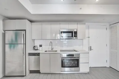 a kitchen with white cabinets and a stainless steel refrigerator at Beachwalk Resort in Hallandale Beach