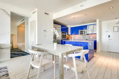 a kitchen with blue cabinets and a white table and chairs at Balcony with Ocean View Fort Lauderdale Oasis! in Fort Lauderdale