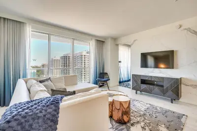 a living room with a white couch and a tv at Walk to Beach and Dining! Luxe Fort Lauderdale Condo in Fort Lauderdale