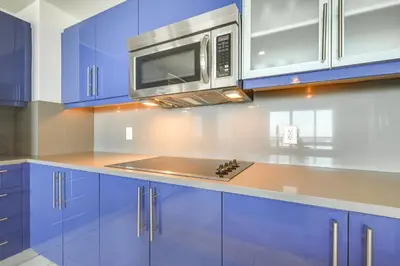 a kitchen with blue cabinets and a microwave at Walk to Beach and Dining! Luxe Fort Lauderdale Condo in Fort Lauderdale