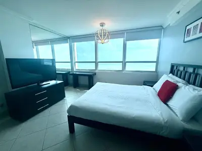 a bedroom with a bed and a flat screen tv at Castle 732 Ocean View with pool, tennis, beach access, FREE parking in Miami Beach