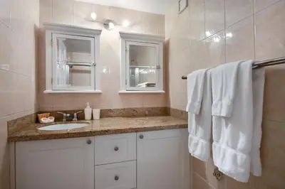 a white bathroom with a sink and a mirror at Castle 732 Ocean View with pool, tennis, beach access, FREE parking in Miami Beach