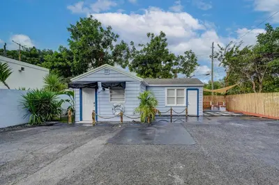 a blue house with a gate in a parking lot at Hidden Getaway in Fort Lauderdale