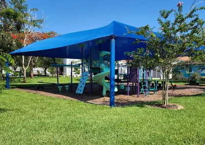 a playground with a blue canopy and a slide at Hidden Getaway in Fort Lauderdale