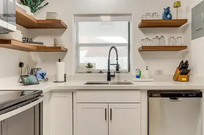 a kitchen with white cabinets and a sink and a window at The Peacock Bungalow Near Fort Lauderdale Beach! in Fort Lauderdale