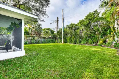 a yard with a green lawn next to a house at The Peacock Bungalow Near Fort Lauderdale Beach! in Fort Lauderdale