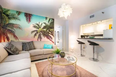 a living room with a couch and a palm tree mural at Cozy Apartment on South Beach in Miami Beach