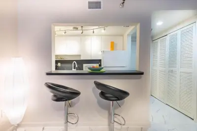 a kitchen with two black stools at a counter at Cozy Apartment on South Beach in Miami Beach