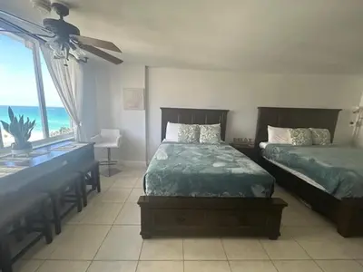 a bedroom with two beds and a desk and a window at Beach Escape private studio in Sunny Isles Beach