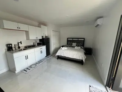 a bedroom with a bed and a kitchen with white cabinets at Luxury Studio in Miami