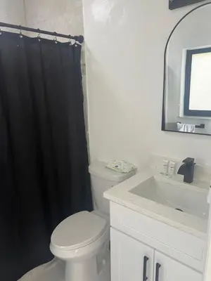 a bathroom with a white toilet and a black shower curtain at Luxury Studio in Miami