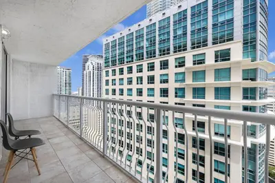 a chair on a balcony with a tall building at Exclusive 1BR Apartment on 35th floor in Miami