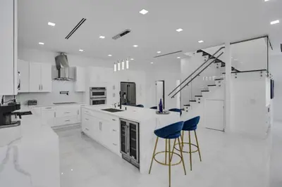 a kitchen with white cabinets and blue bar stools at 4 BR Designer Home Next to Shul and Community Pool villa in Fort Lauderdale