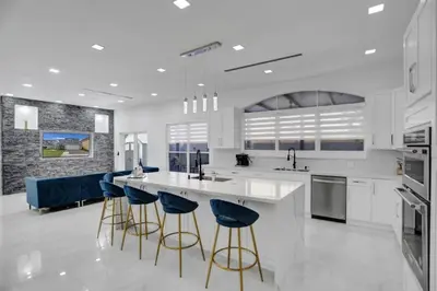 a kitchen with white counters and blue bar stools at 4 BR Designer Home Next to Shul and Community Pool villa in Fort Lauderdale