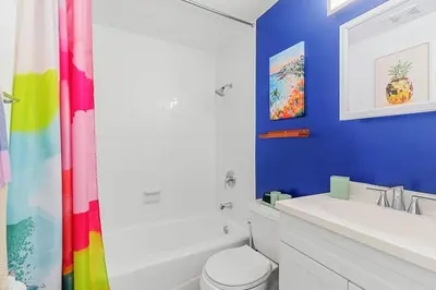 a bathroom with a rainbow shower curtain and a white toilet at Chic Getaway Near Wilton Drive l Your Urban Escape in Fort Lauderdale