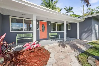 a house with an orange door and two benches at Chic Getaway Near Wilton Drive l Your Urban Escape in Fort Lauderdale