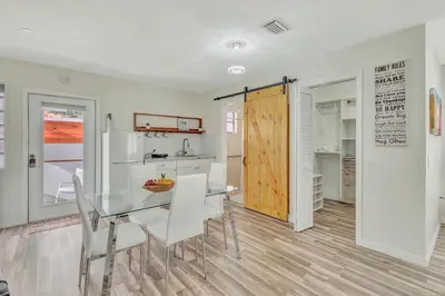 a kitchen and dining room with a glass table and white chairs at Dreams Studio in Hialeah