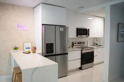 a kitchen with white cabinets and a refrigerator at Villa Roads - Ideal Stay in Miami - King - Bed Parking - Near Airport, Brickell, Coconut Grove, Little Havana, Wynwood & Calle 8 in Miami