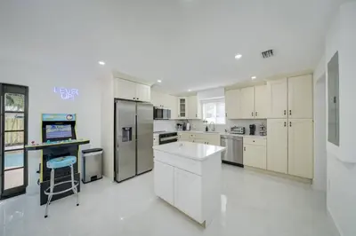 a kitchen with white cabinets and a refrigerator at Home with Games Pool Paradise in Fort Lauderdale