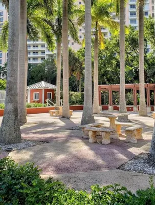 a park with benches and palm trees in front of a building at Key Biscayne Beach Vacation in Miami