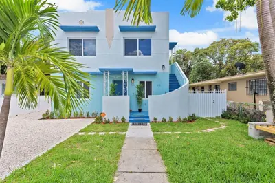 a blue house with a white fence and palm trees at Celeste House Enjoy Caribbean 2 BR APT in Miami