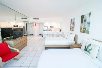 a hotel room with two beds and a red chair at Castle 1133 Ocean view studio, Pool and Beach Access, FREE Parking, Tennis and more! in Miami Beach
