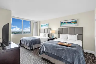 a hotel room with two beds and a flat screen tv at Gallery One Resort Access Fort Lauderdale Beach in Fort Lauderdale