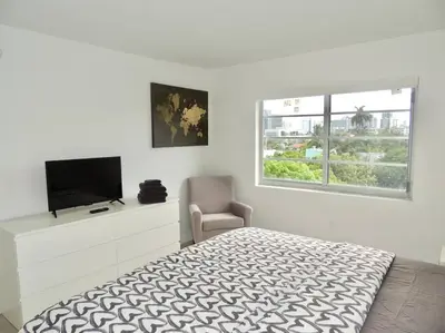 a bedroom with a bed and a tv and a window at 2BR in Heart of SoBe with Parking in Miami Beach