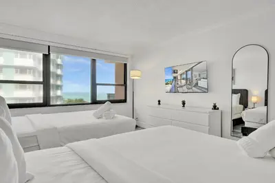 a white bedroom with two beds and two mirrors at Charming Ocean View Condo Beach Service 806 in Miami Beach