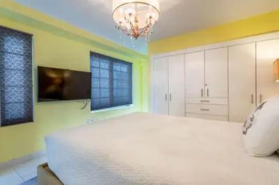 a bedroom with a large white bed and a chandelier at Luxury Large 1BR at The Carlyle SoBe Sleeps 4 in Miami Beach