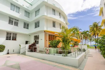 a white house with palm trees in front of it at Luxury Large 1BR at The Carlyle SoBe Sleeps 4 in Miami Beach
