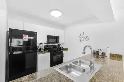 a kitchen with a sink and a black refrigerator at Condo Stylish and Minimalist w Highlights Amenities! in Miami