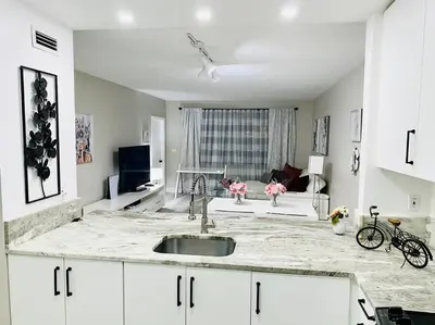 a kitchen with a sink and a living room at Modern 1BR 1BA Condo 1Block to Aventura Mall in Aventura