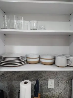 a white shelf with plates and bowls on it at Amazing Deal! Dania Beach Home with Pool & Jacuzzi in Dania Beach