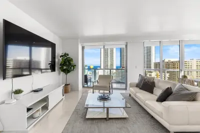 a living room with a couch and a tv at Escape to Beachwalk Resort in Chic Apartment in Hallandale Beach