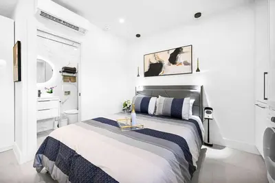 a white bedroom with a bed and a bathroom at Modern Oasis Near Design District, Wynwood in Miami