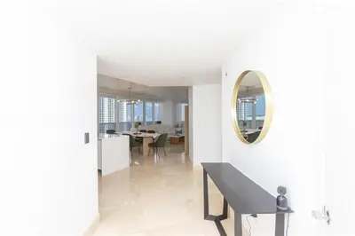 a white hallway with a bench and a mirror at Elegant Resort - Beautiful Views in Hallandale Beach