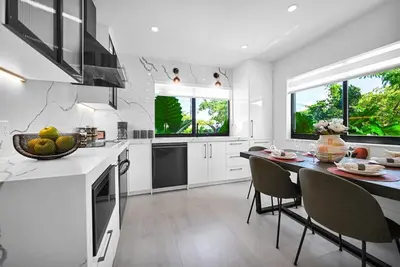 a white kitchen with a table and chairs in it at Modern Private Oasis by Design District & Wynwood in Miami