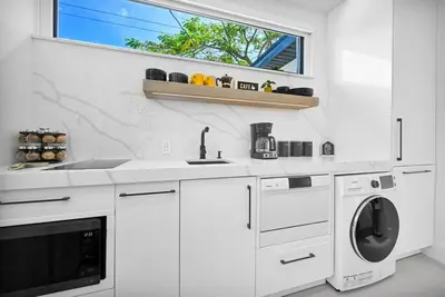a white kitchen with a washing machine and a window at Modern Studio Near Design District, Wynwood in Miami