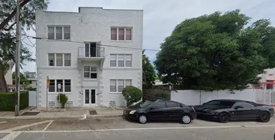 two cars parked in front of a white building at The Tiny Red Mini Studio At Little Havana in Miami