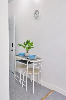 a white table with chairs and a clock on a wall at The Tiny Red Mini Studio At Little Havana in Miami