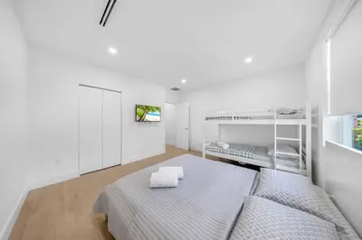 a white bedroom with two bunk beds and a tv at Up to 12 guests! Modern Villa near Wynwood 29! in Miami