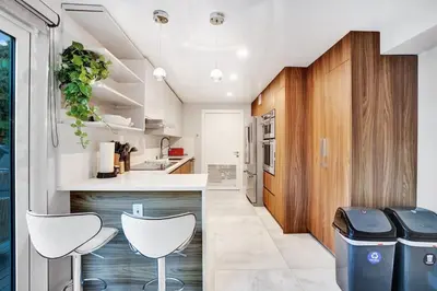 a kitchen with white counters and white stools at Ultimate Retreat 6BR & 3BA Villa near Beach in Dania Beach