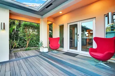 two red chairs on a porch with sliding glass doors at Ultimate Retreat 6BR & 3BA Villa near Beach in Dania Beach