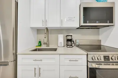 a kitchen with white cabinets and a sink at ULTRA peaceful 2 bedroom beach&boardwalk apartment in Hollywood