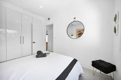 a white bedroom with a bed and a mirror at Stylish Oasis in Design District, Near Wynwood in Miami