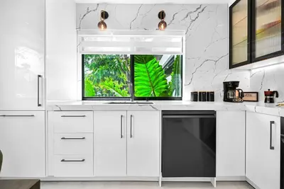 a white kitchen with a sink and a window at Stylish Modern Home near Wynwood & Design District in Miami